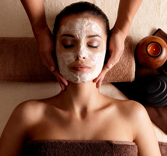 Spa massage for woman with facial mask on face